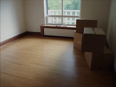 An empty room with a hardwood floor, moving boxes and keys on the window sill